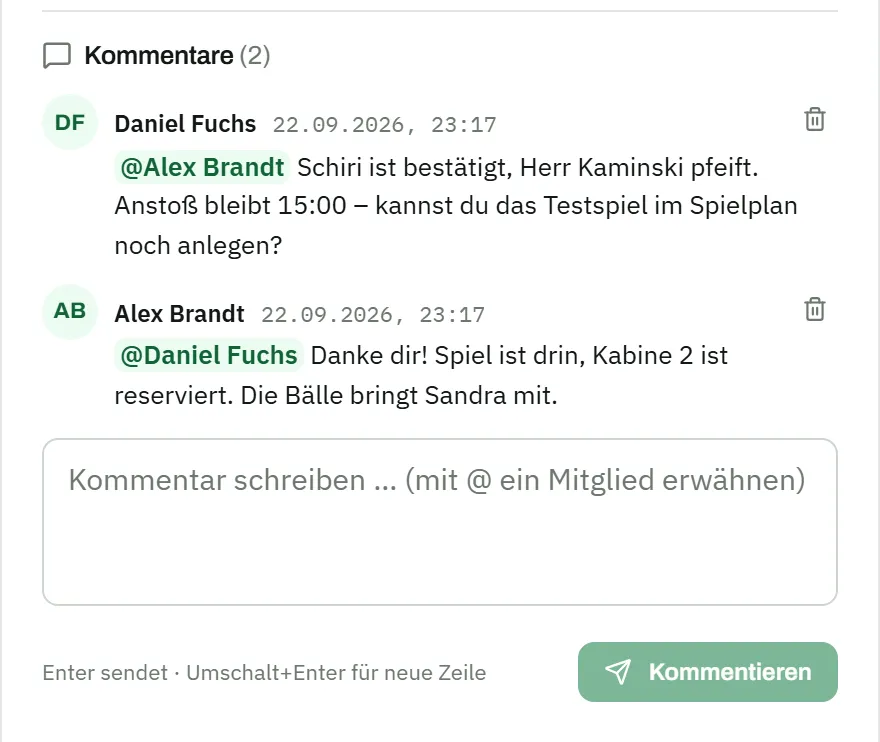Kommentare zu einer Aufgabe: Daniel Fuchs schreibt an @Alex Brandt, der Schiri sei bestätigt, Herr Kaminski pfeife, Anstoß bleibe 15:00, ob er das Testspiel im Spielplan noch anlegen könne; Alex Brandt antwortet @Daniel Fuchs, das Spiel sei drin, Kabine 2 reserviert, die Bälle bringe Sandra mit; darunter das Eingabefeld „Kommentar schreiben … (mit @ ein Mitglied erwähnen)"